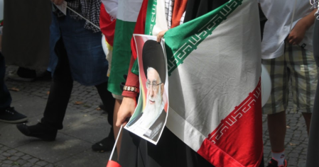 Iranischer Fahnenträger mit Foto des Ayatollah